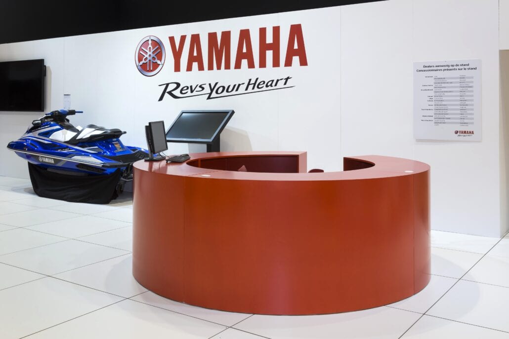 Een grote rode, ronde infobalie bij Yamaha op de beursstand, gerealiseerd door Expo Z standenbouw. ronde infobalie beursstand yamaha Autosalon Brussel