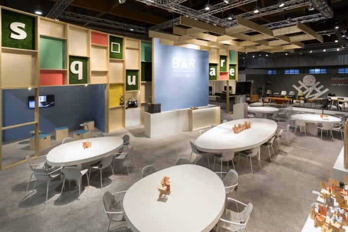 Op maat gemaakte organische tafels door Expo Z standenbouw voor deze beursstand op meubelbeurs Brussel. beursstand met grote bar met ovalen tafels op de Meubelbeurs Brussel
