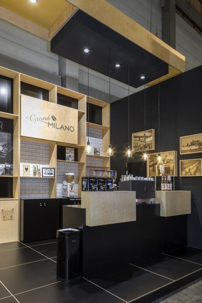 De op maat gemaakte toog en de bergingwand op deze beursstand lopen naadloos over in deze zwarte verhoogde vloer met zwarte plint. print van metrotegels roept meteen het gevoel van een trendy koffiebar op bij deze beursstand