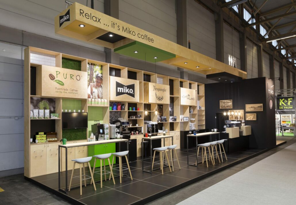 Door de ophanging boven de stand uit te voeren in dezelfde materialen creëert dit een mooie harmonie op de beursstand. beursstand voor Miko, Puro, Bruynooghe en Grand Milano koffie op Horeca Expo Gent